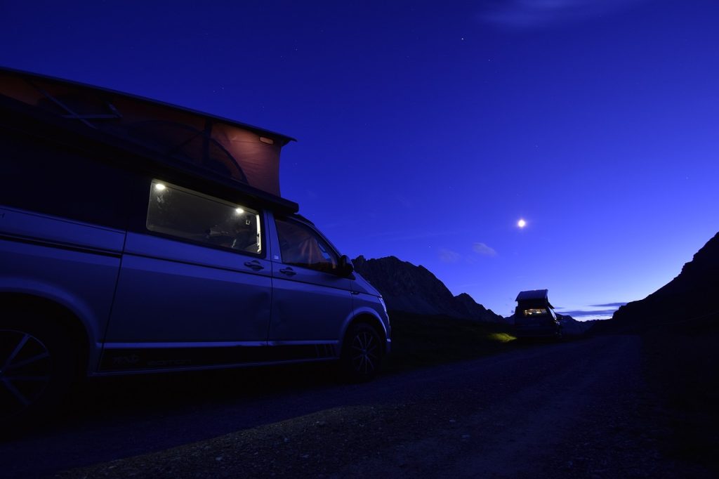 Calefacción en la camper: tipos y seguridad Furgoneta camper aparcada de noche con la luz interior encendida