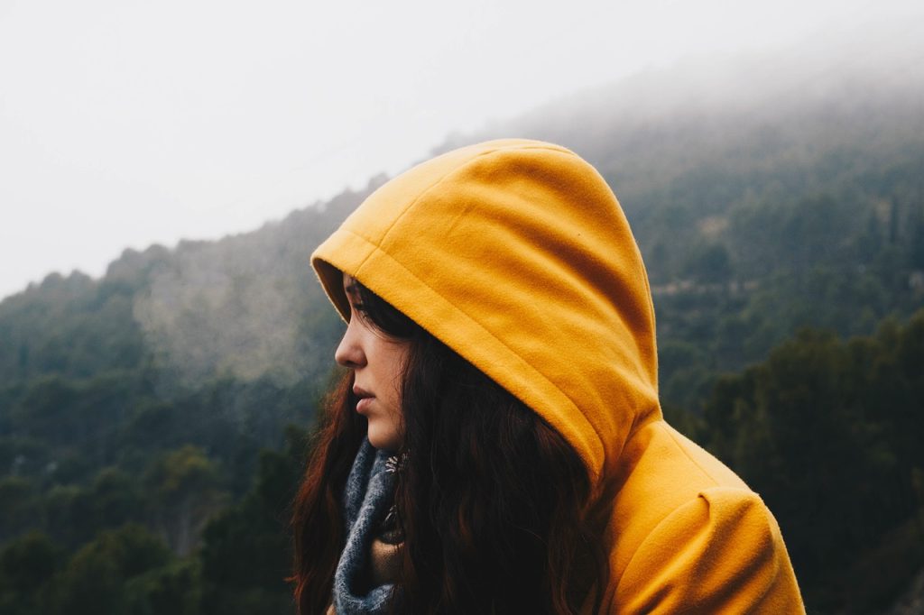 Ropa por capas para viajar en camper en primavera Viajera con sudadera de capucha en la montaña en un día de niebla, ropa por capas