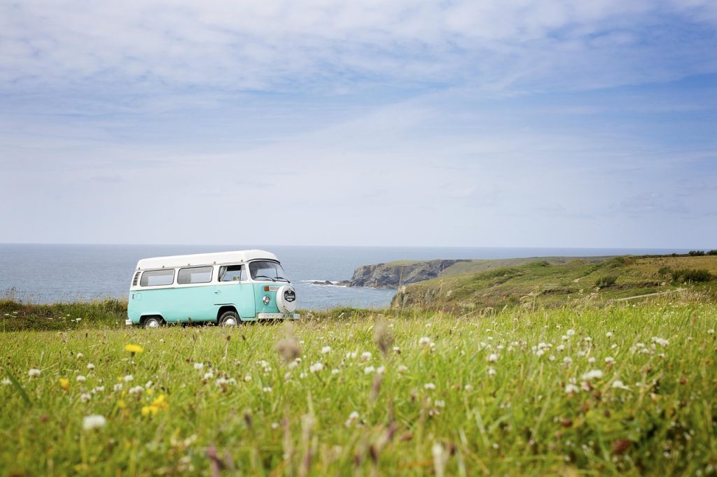 Viajar en camper en septiembre: la mejor época para rodar Furgoneta camper clásica en un prado junto a la costa